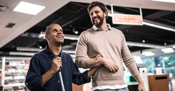 Decorative image: A man assists a blind man walking through a store